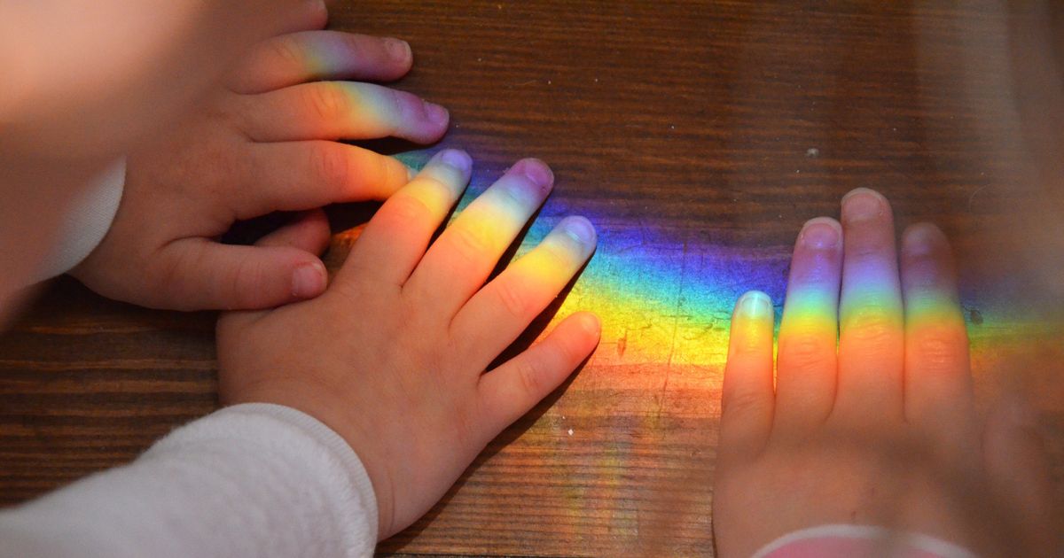 虹の光が子どもの手に映っている様子