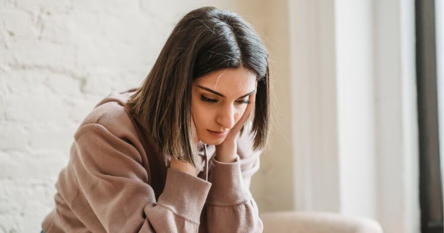 情報が多すぎて悩んでいる女性。頭を抱えて、真剣な表情で何かを見つめている。