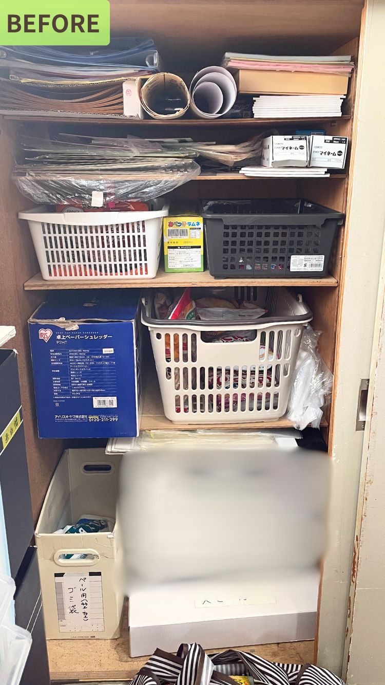 学童施設内の収納棚のフォー写真。棚には紙類、書類、箱入りお菓子などが無造作に置かれており、バラバラなバスケットやダンボール箱が使われています。