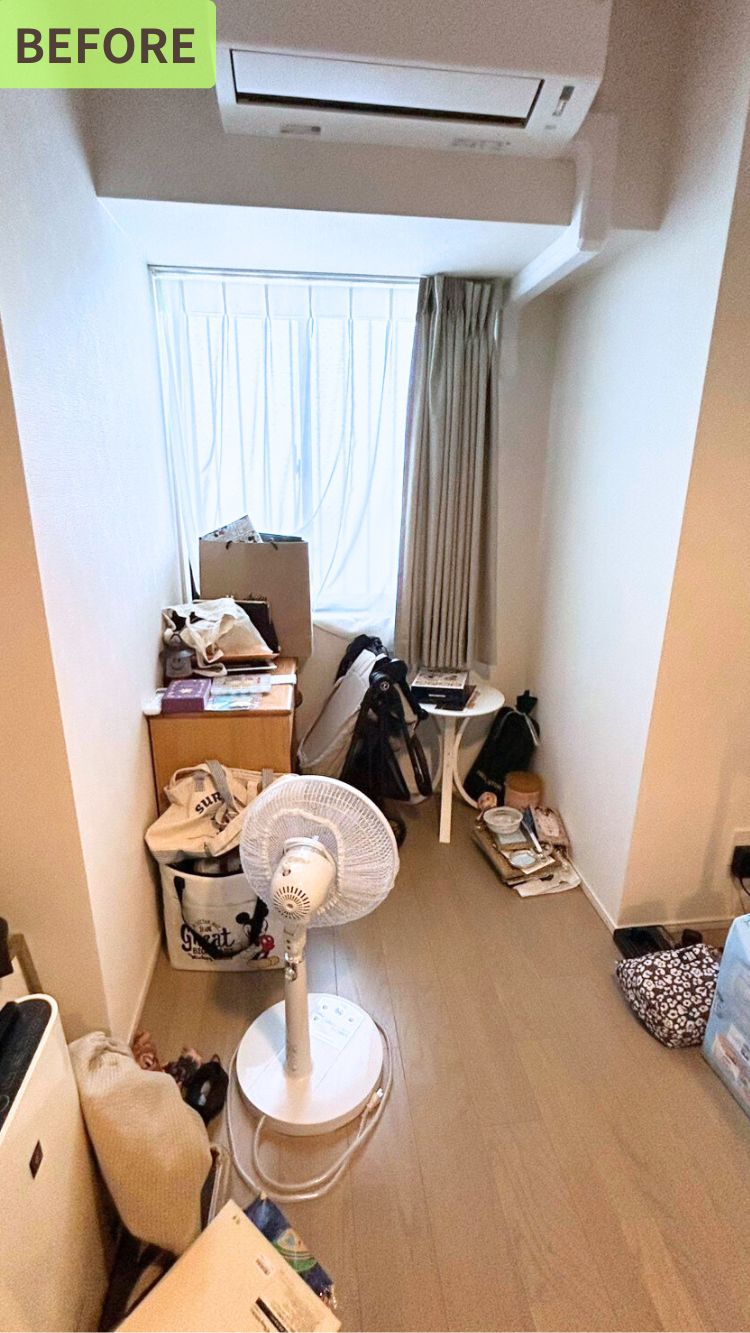 窓際にモノが集中している状態のビフォー写真。扇風機、バッグ、テーブルなど積まれた雑誌などが床に置かれ、生活動線が悪い状態である。