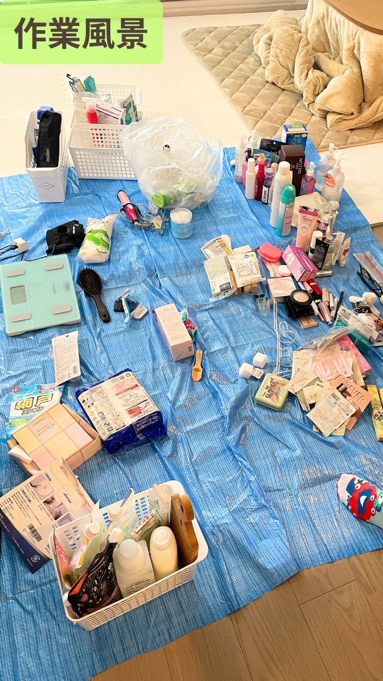 ブルーシートの上に日用品や化粧品が広げられた整理収納サポート中の作業風景。スキンケア用品やヘアブラシ、電動シェーバーなどが分類されて並べられている。